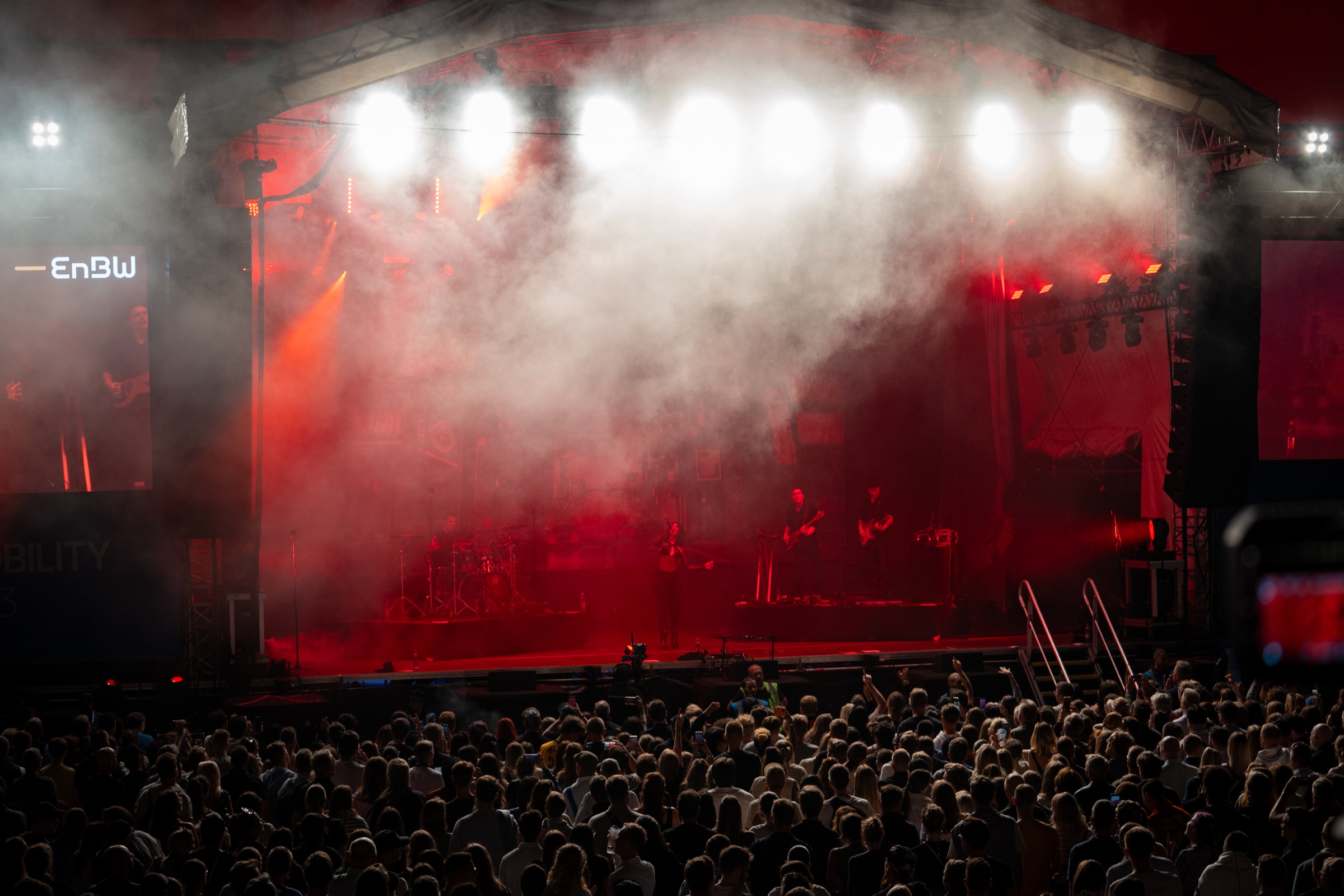 Eventfotografie einer rot illuminierten Konzertbühne mit großem Publikum